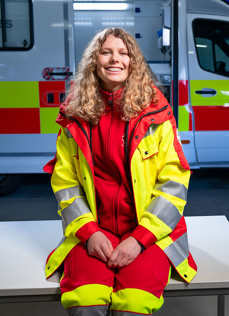 Junge Notfallsanitäterin lächelt in die Kamera.