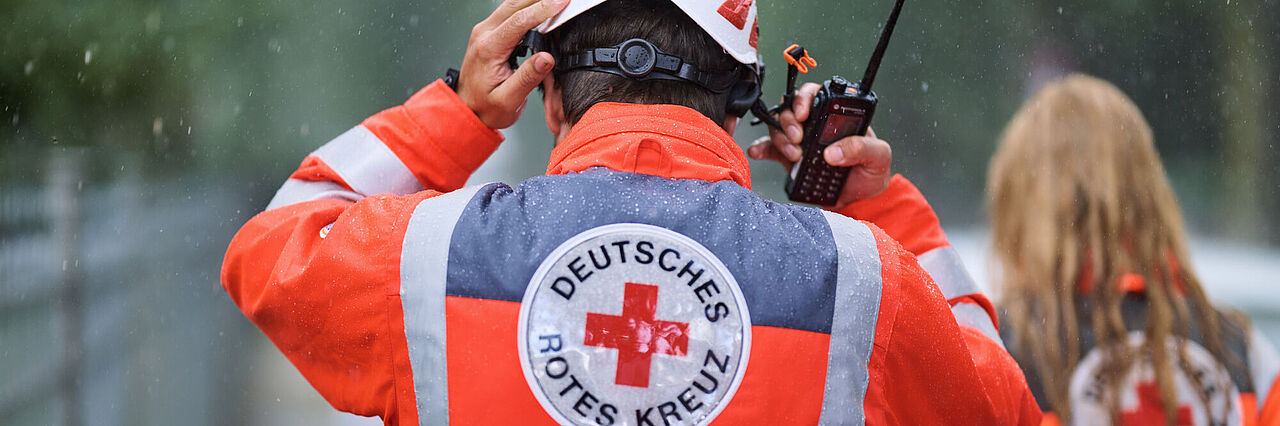 Ehrenamtlicher setzt sich Helm bei Regen auf.
