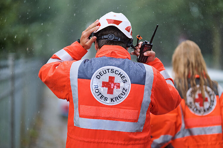 Ehrenamtlicher setzt sich Helm bei Regen auf.
