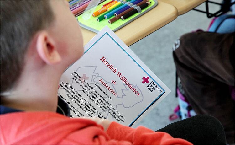 Ein Schüler hält die Ernennungsurkunde zum Juniorhelfer in der Hand.