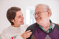 DRK-Mitarbeiterin mit älterem Mann, lachend