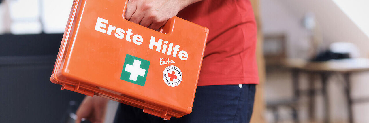 Mann trägt Erste-Hilfe-Koffer
