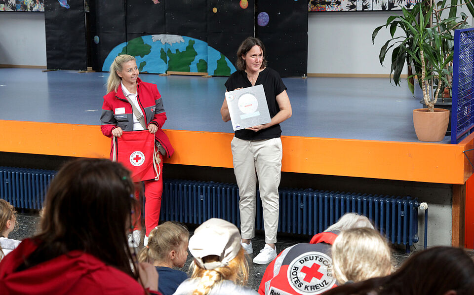 Inna Bernwald vom DRK und Lehrkraft Pütz bei der Übergabe der Plakette.