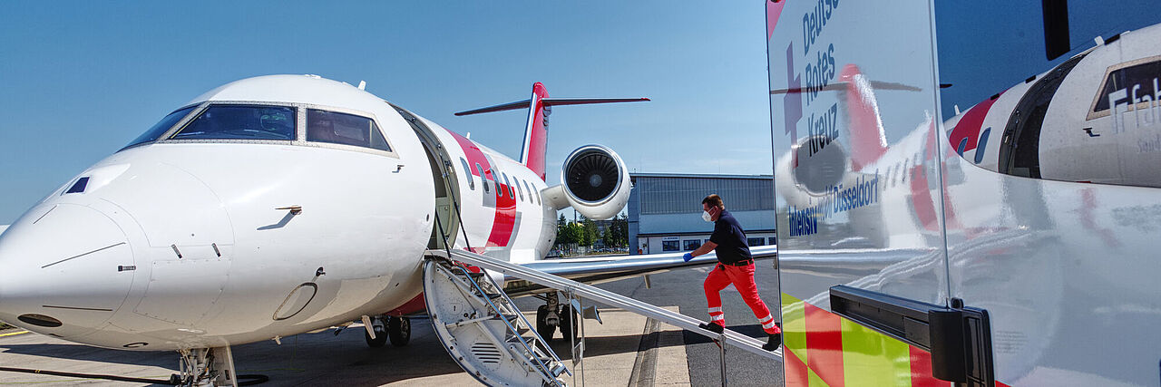 Ein Flugzeug und ein Rettungswagen stehen auf dem Flugfeld.