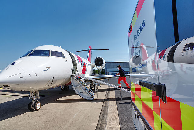 Ein Flugzeug und ein Rettungswagen stehen auf dem Flugfeld.