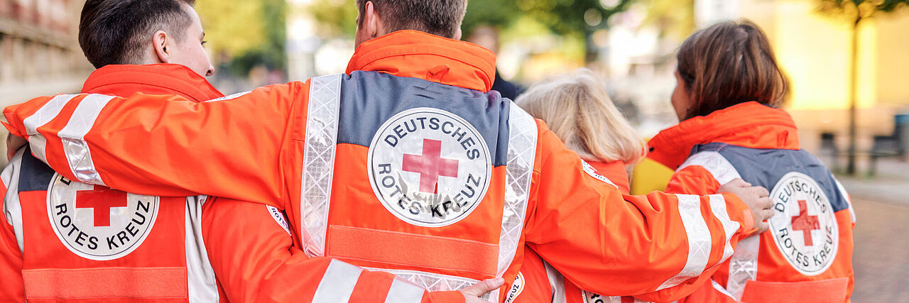 Vier DRKler mit Einsatzjacken von hinten im Arm
