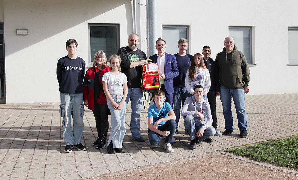 Sandra Scheible, DRK-Kreisverband Pforzheim-Enzkreis e.V. (2.v.l.), Alex Kirchhardt, zuständige Lehrkraft für den Schulsanitätsdienst an der Kirnbachschule (4 v.l.), Timo Fahrer, Regionalgeschäftsführer bei der BARMER Pforzheim, (hinten, 5.v.l.) und Florian Dietz, ebenfalls zuständige Lehrkraft (ganz rechts). Foto: Susan Miersch/DRK-Kreisverband Pforzheim-Enzkreis e.V.